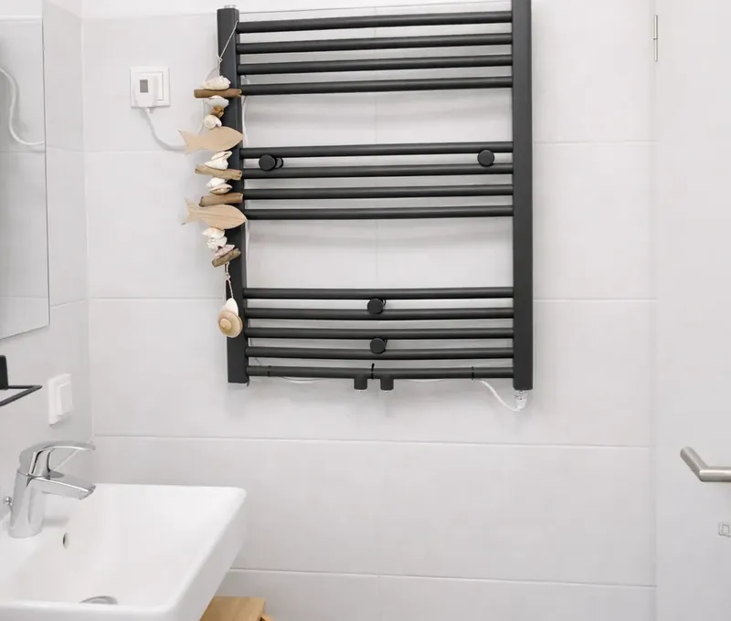 Badezimmer im Ferienhaus Seeblick mit Waschbecken und schwarzem Handtuchheizk&ouml;rper.