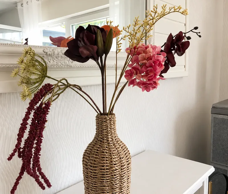 Dekorative Vase mit Blumen im Haus am See vor hellem Innenraum.