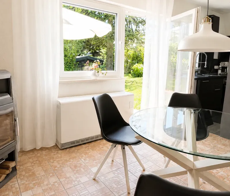 Essbereich im Haus am See mit Blick zum Fenster und in die offene Kueche.