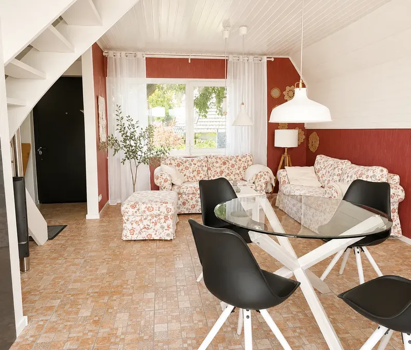 Wohn- und Essbereich im Haus am See mit Sofa, Esstisch und Treppe zur Galerie.