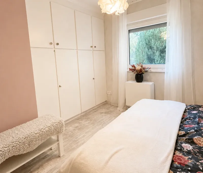 Schlafzimmer im Haus am See mit Doppelbett, Kleiderschrank und Fenster.