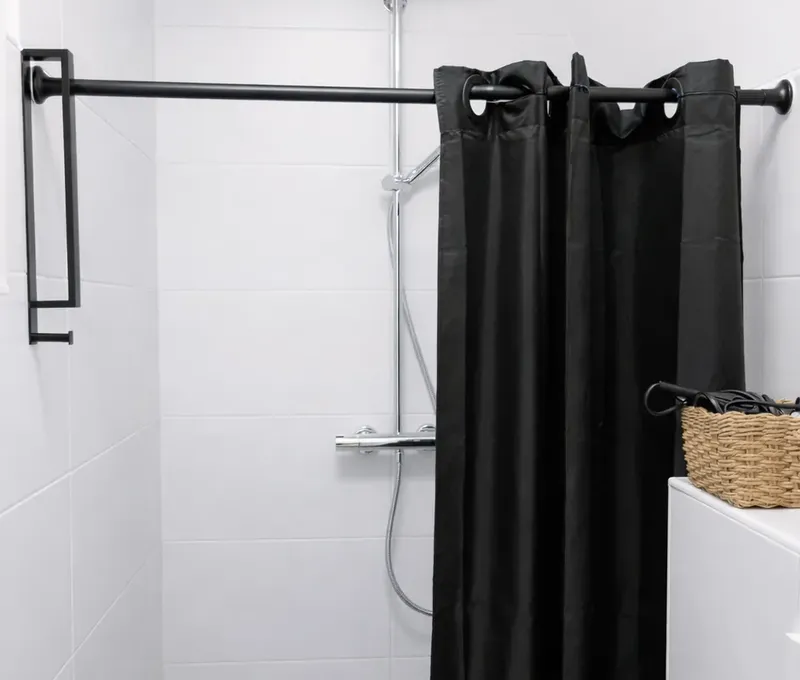 Dusche im Badezimmer des Ferienhauses Seeblick mit schwarzem Duschvorhang.