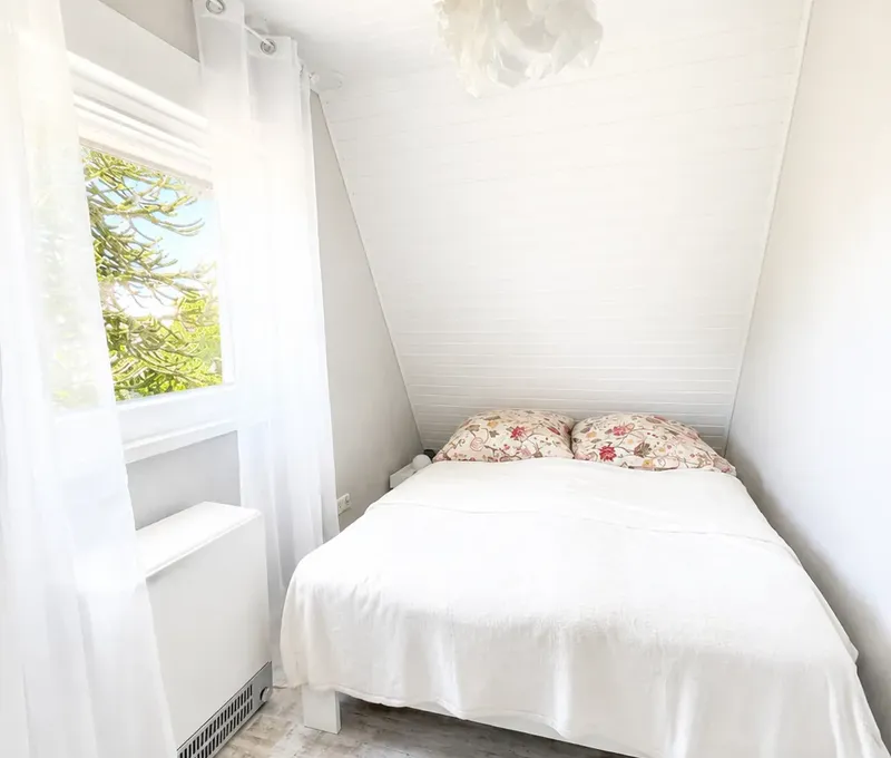 Helles Schlafzimmer im Haus am See mit Doppelbett und Fenster.