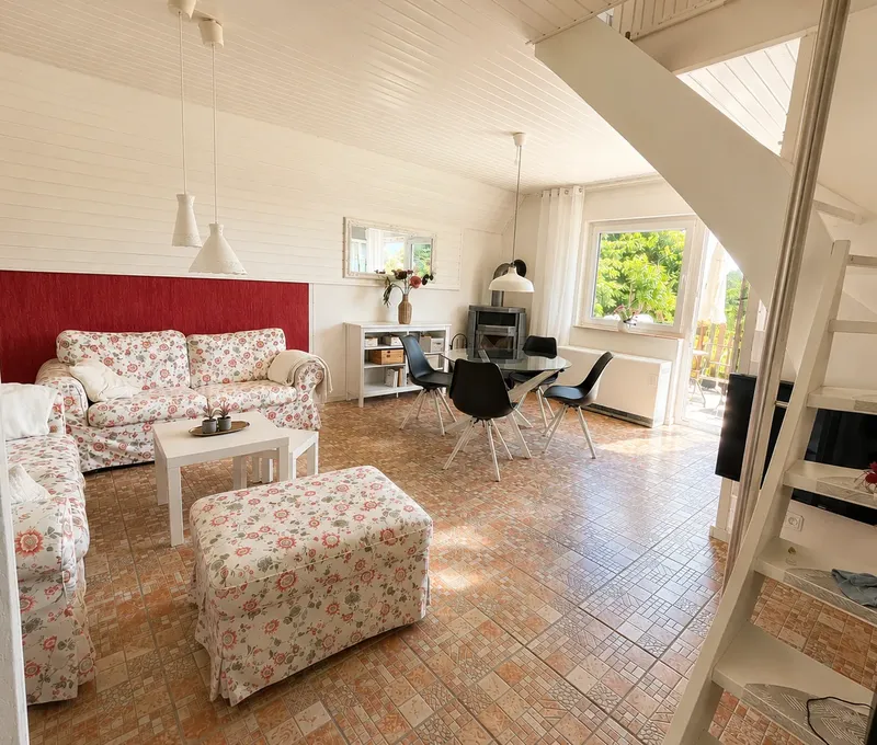 Wohnzimmer im Haus am See mit Sofa, Treppe und Galeriegeschoss.