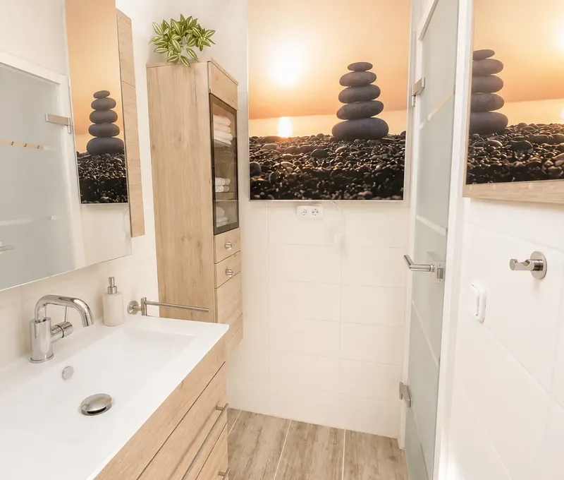 Badezimmer im Haus am See mit Waschbecken, Spiegel und Dusche.
