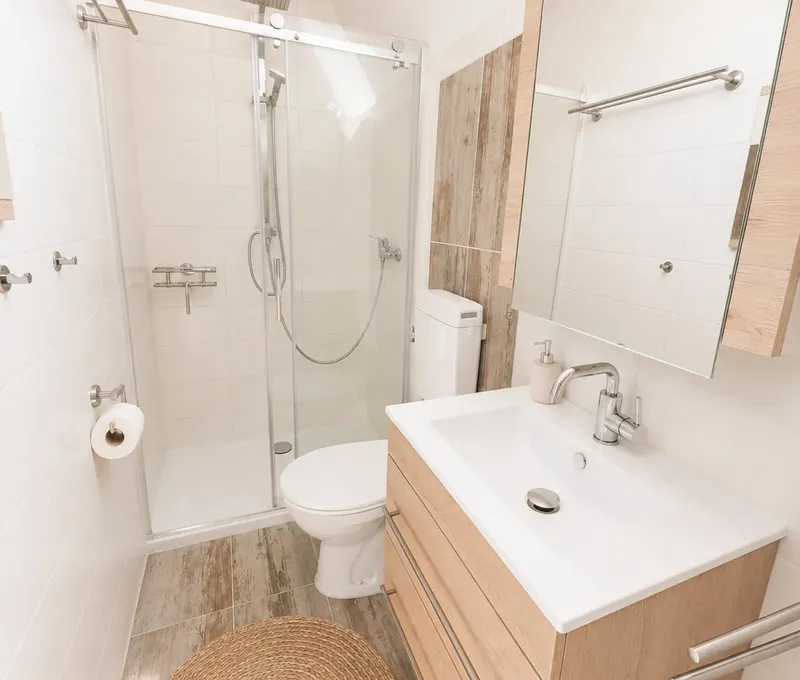 Badezimmer im Haus am See mit Dusche, Waschbecken und hellem Spiegelbereich.