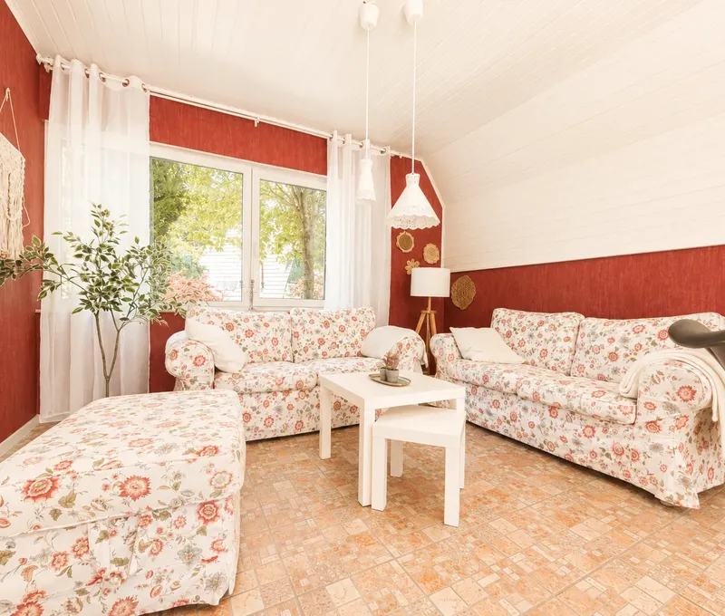 Gemutliches Wohnzimmer im Haus am See mit Sofa, Couchtisch und roten Akzentwaenden.