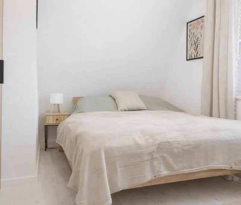 Schlafzimmer im Ferienhaus Seeblick mit Doppelbett, Nachttisch und hellen Vorh&auml;ngen.